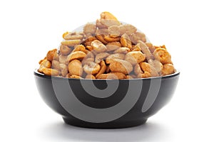 Close-up of Heeng jeera Peanuts mixture Indian namkeen snacks in black bowl over white background.