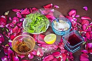 Close up of a herbal face pack consisting of Aloe Vera gel,honey,milk cream,lemon and rose with rose water and rose petals on wood