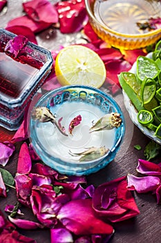 Close up of a herbal face pack consisting of Aloe Vera gel,honey,milk cream,lemon and rose with rose water and rose petals on wood