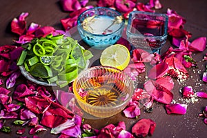 Close up of a herbal face pack consisting of Aloe Vera gel,honey,milk cream,lemon and rose with rose water and rose petals on wood