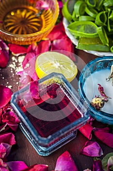 Close up of a herbal face pack consisting of Aloe Vera gel,honey,milk cream,lemon and rose with rose water and rose petals on wood