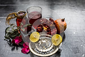 Close up of herbal face pack of pomegranate and lemon juice with rose water on wooden surface with some sliced lemons and pomegran