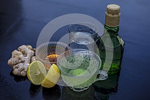 Close up of herbal green tea consisting of whiskey, ginger,honey,water,lemon and mint in a transparent cup on wooden surface.