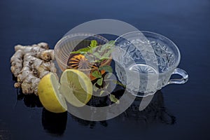 Close up of herbal green tea consisting of whiskey, ginger,honey,water,lemon and mint in a transparent cup on wooden surface.