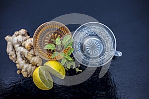 Close up of herbal green tea consisting of whiskey, ginger,honey,water,lemon and mint in a transparent cup on wooden surface.