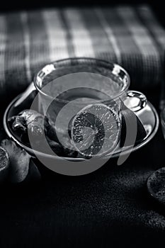 Close up of a herbal tea  consisting of apple juice,lemon,ginger and warm water in a transparent cup on a wooden surface in dark G