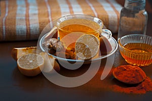 Close up of a herbal tea  consisting of apple juice,lemon,ginger and warm water in a transparent cup on a wooden surface in dark G