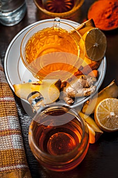 Close up of a herbal tea  consisting of apple juice,lemon,ginger and warm water in a transparent cup on a wooden surface in dark G