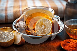 Close up of a herbal tea  consisting of apple juice,lemon,ginger and warm water in a transparent cup on a wooden surface in dark G