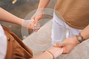 Close-up high-angle cropped shot of unrecognizable loving married couple standing holding hands outdoors on summer day.