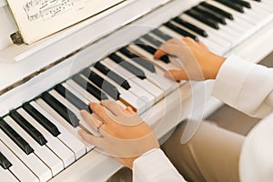 Close-up high-angle view of unrecognizable female musician performer playing on classical piano at home enjoying