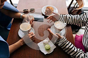 Close-up high-angle view of unrecognizable two happy female girlfriends sharing news, planning weekend, enjoy pleasant