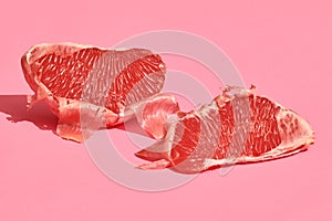 Close up high quality image of peeled slices of juicy grapefruit on a pink background