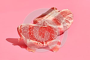 Close up high quality image of peeled slices of juicy grapefruit on a pink background