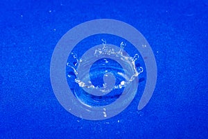 Close up. High speed photography. Drops of water form a water crown. Blue background