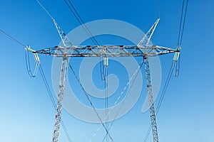 Close-up of a high voltage power line pole isolated against clear blue sky. No visible horizon