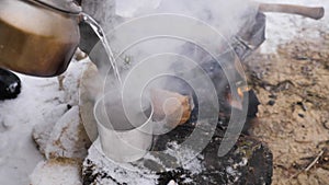 Close up of hiker pouring boiling water from kettle into tea cup outdoor