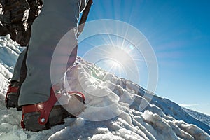 Close up of hiking shoes with crampons and ice axe.