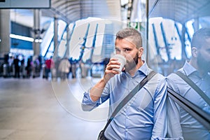 Close up of hipster businessman drinking coffee, subway station