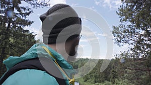 Close up of hipster hiker observing the the green valley on blue cloudy sky background. Stock footage. A bearded man