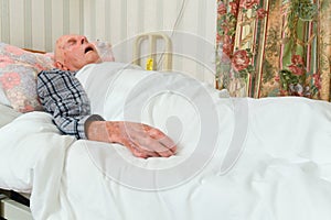 Elderly infirm man lying asleep in bed after being discharged from hospital photo