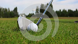 Close-up of hitting a golf club on a ball against a forest background