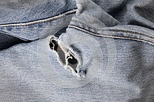 Close up of hole in an old pair of blue jeans