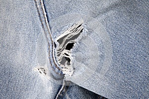 Close up of hole in an old pair of blue jeans