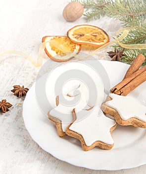 Close up of homemade butter nuts star shaped cookies with icing, pine, orange slices,cinnamon, anise, walnuts and golden ribbon