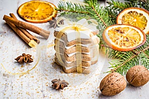 Close up of homemade butter nuts star shaped cookies with icing, pine, orange slices,cinnamon, anise, walnuts and golden ribbon