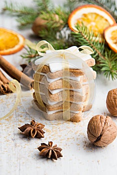 Close up of homemade butter nuts star shaped cookies with icing, pine, orange slices,cinnamon, anise, walnuts and golden ribbon