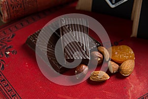 Close-up of a homemade chocolate bar with raisins, dried apricot and nuts on red book background