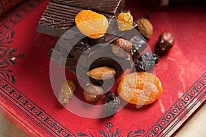 Close-up of a homemade chocolate bar with raisins, dried apricot and nuts on red book background