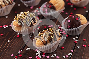 Close-up homemade cookies shaped nuts with cream, chocolate icing on wooden table as a background, red, rose and white sugar