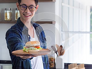 Close-up of a homemade hamburger on wooden dish holding by young man