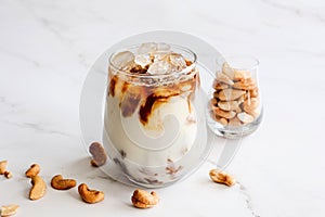 Close up homemade iced latte with plant base milk cashew nut milk with cashew nuts decorated on light background. Self care Health