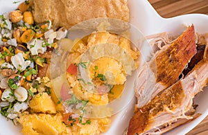 Close up of homemade mashed potatoes with salad, tostado, mote and sliced pieces of hornado photo