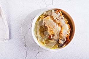 Close up of homemade onion soup with croutons and cheese in a bowl on the table top view