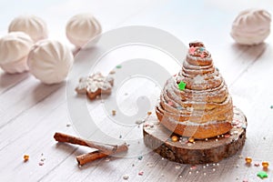 Close-up homemade sweet Christmas cinnamon roll bun white wood table.