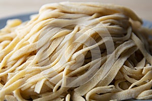 Close up Homemade uncooked pasta noodle with flour over grey background. Food background. Copy space for text