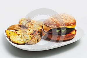 Close-up of homemade vegan cheeseburger and roasted potatoes with rosemary.