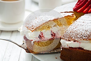 Close up of homemade Victoria sponge cake filled with strawberries, jam and whipped cream
