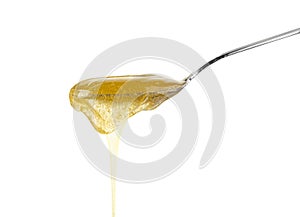 Close up honey flowing from metal spoon on white photo