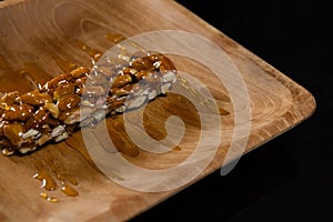 Honey on granola bar in wooden plate