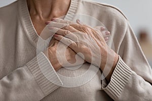 Close up hopeful grateful mature woman keeping hands on chest