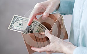 Close up of hopeless woman open her empty wallet and found only one dollar bill.