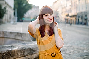 Close up horizontal shot of beautiful stylish Caucasian woman in the old city, wearing stylisch yellow clothes, looking