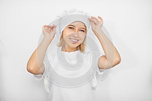 Close up horizontal studio shot of young attractive female pastry chef, wearing white uniform, har and apron, posing to