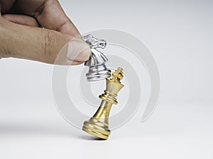 Close-up horse, silver knight chess piece attack the gold king isolated on white background.