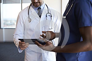 Close Up Of Hospital Staff Reviewing Notes On Digital Tablet